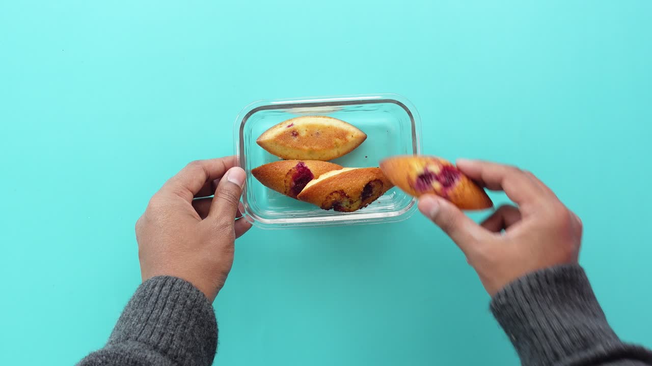 cerca de las manos sosteniendo un recipiente con 3 pasteles llenos de frambuesa