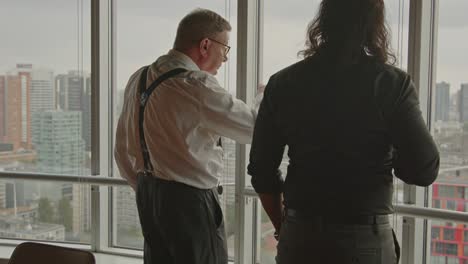 two businessmen discussing business strategy while looking out over city skyline