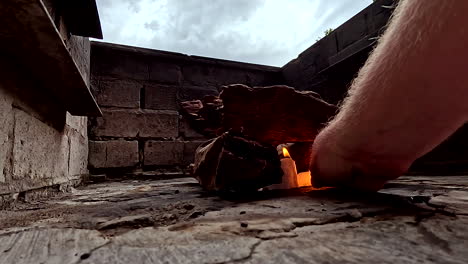 man ignites fire starters under wood stack in outdoor braai fire pit
