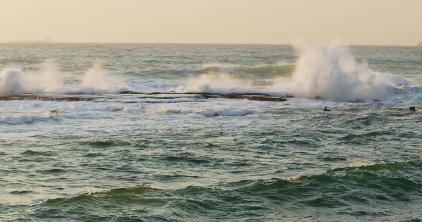 Beautiful yellow sunset sky over the Indian ocean, Durban Kwazulu-Natal South Africa. Summer sunset seascape with Waves crash on silhouette rocks from left to right.