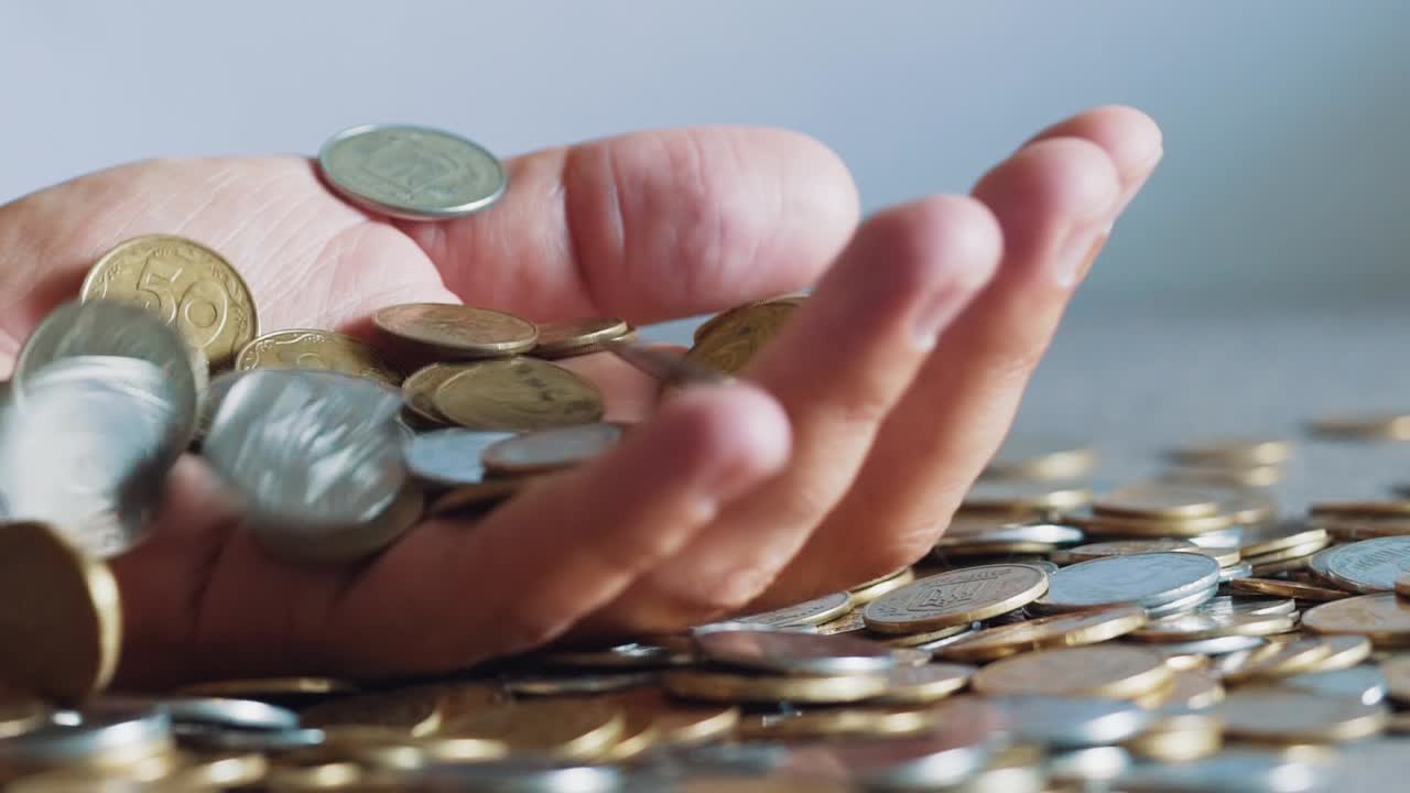 Lot of coins in the hands of men, symbolizing wealth. Slow motion