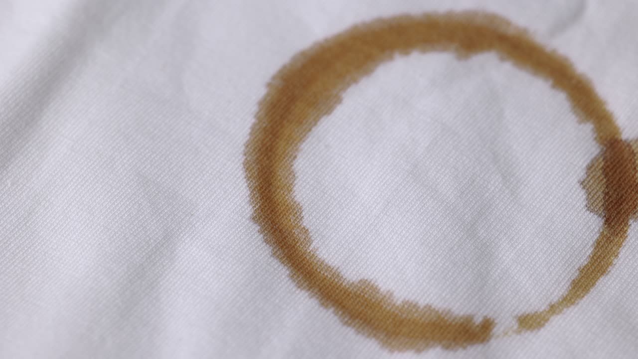 A white cotton shirt stained with brown coffee stains. Must be washed thoroughly in the washing machine