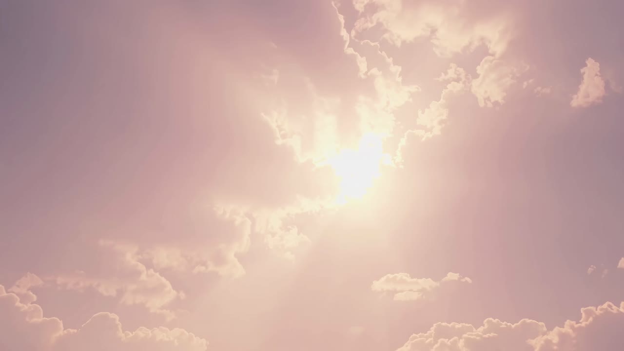 A serene video scene of a bright sun shining through fluffy clouds, captured from a low-angle