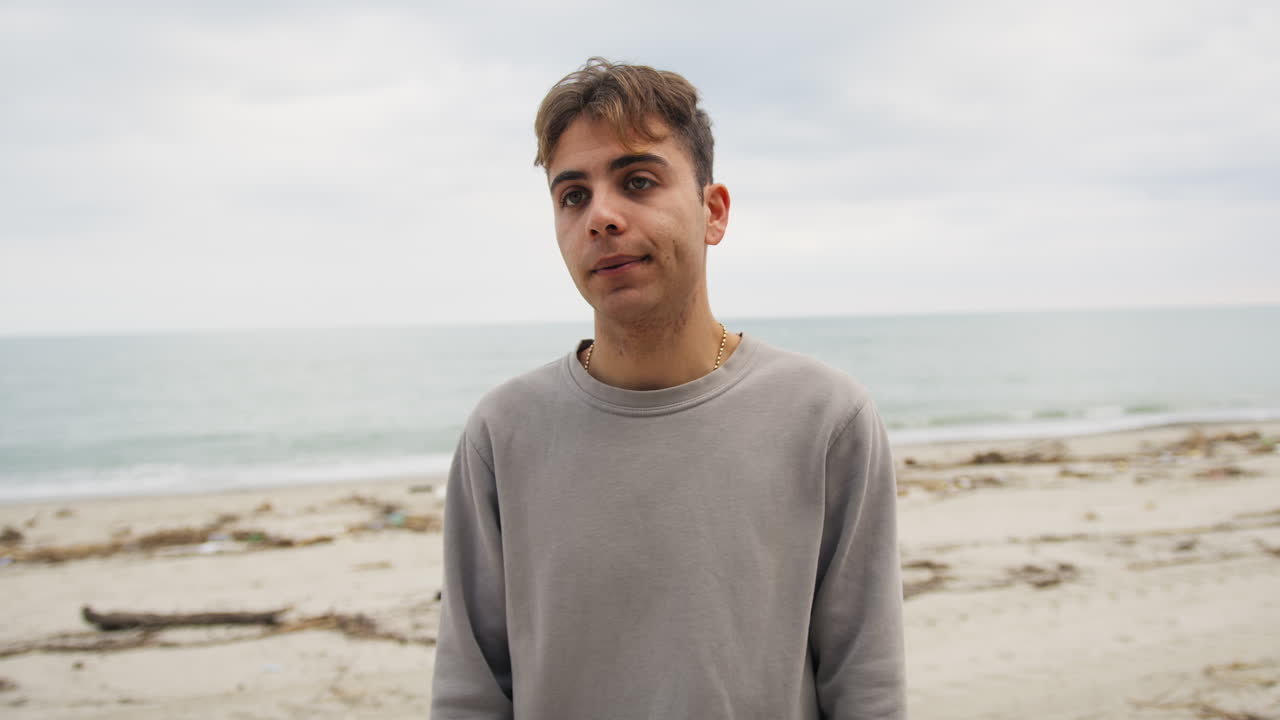 niño se encoge de hombros con esperanza mientras habla con un amigo en la playa cielo nublado