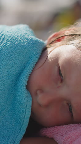 cute little child covered with soft towel awakes napping on deck chair after games on beach on sunny summer day close view slow motion