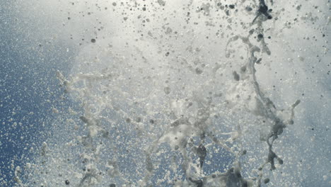 slow motion water spray pattern from blowhole forms organic arc against light ocean sky