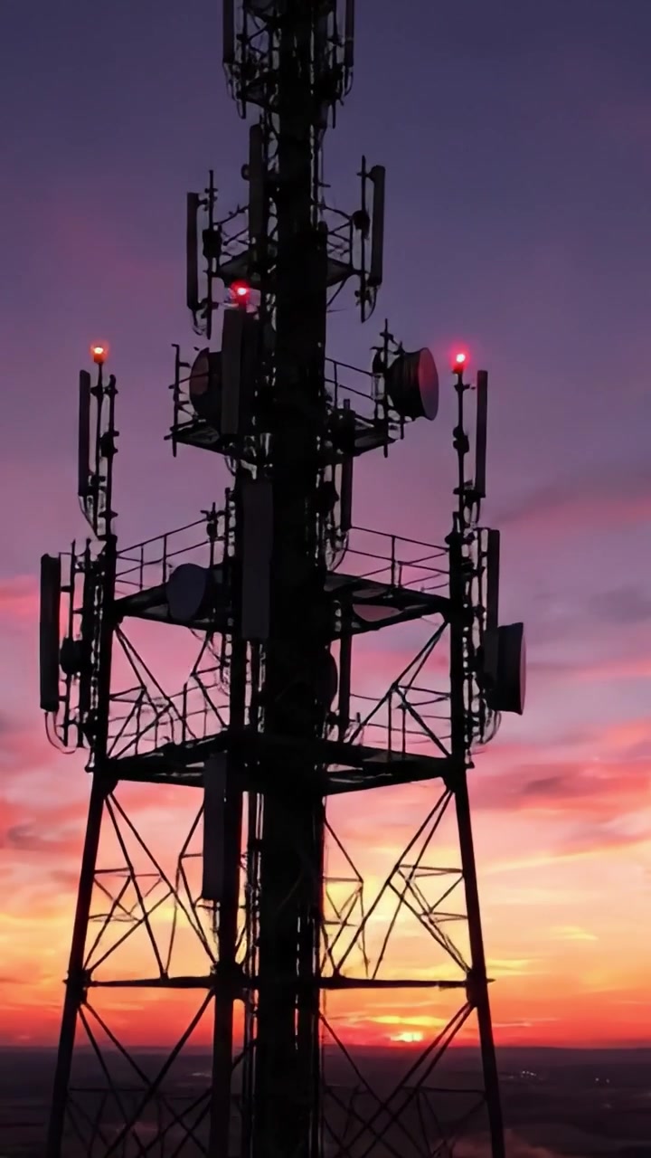 Un Tramonto Mozzafiato su una Torre di Comunicazione Stagliata Contro il Cielo Vibrante Rosa e Arancione, che Cattura la Bellezza della Tecnologia e dello Spettacolo Serale della Natura
