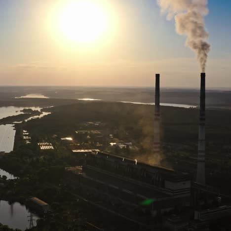 dark silhouette of a factory at sunset. manufacture releases harmful smoke into the air. nature in danger. industrial plant near the river in the evening.