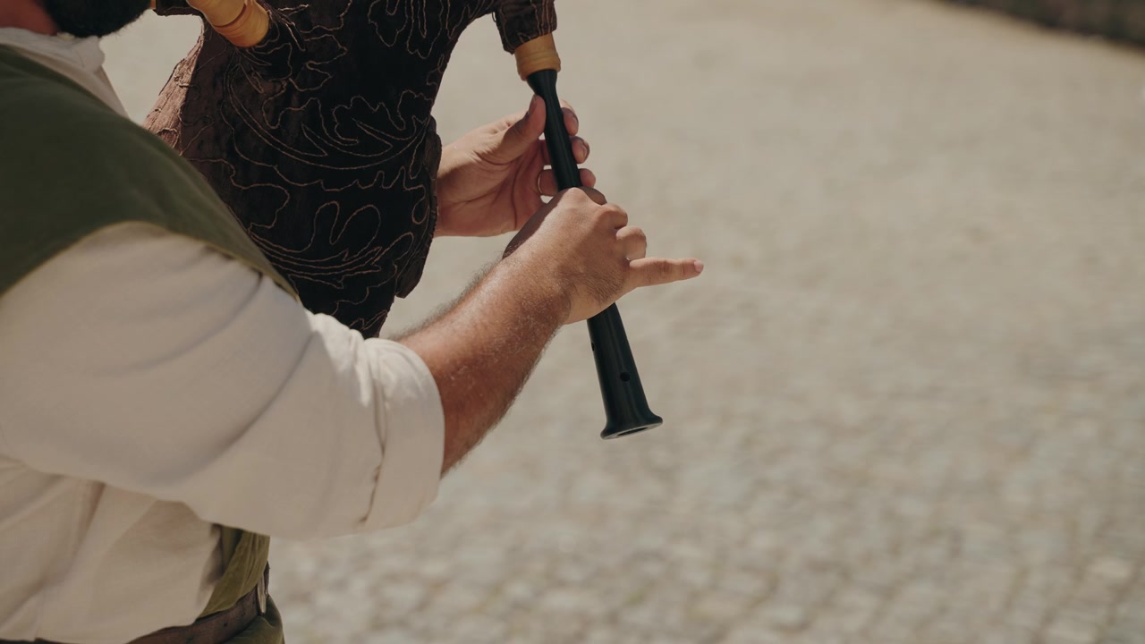 Primo piano di un musicista che suona una cornamusa decorata durante uno spettacolo musicale culturale all'aperto.
