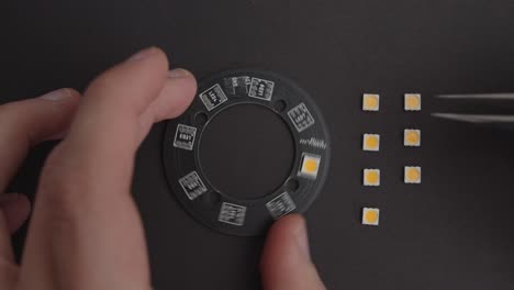 placing electronics components on black pcb with tweezers top view