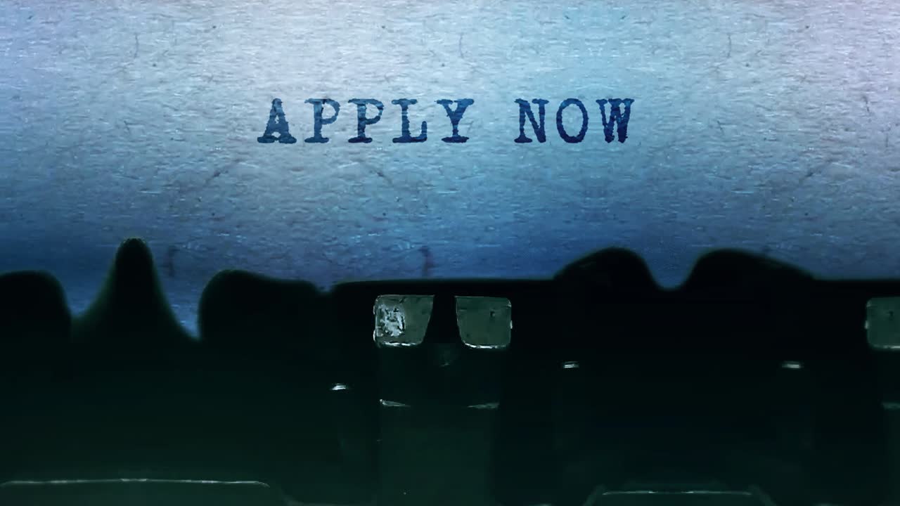 Apply now word closeup being typing and centered on a sheet of paper on old vintage typewriter