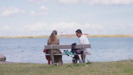 couple relaxing on a bench by the water