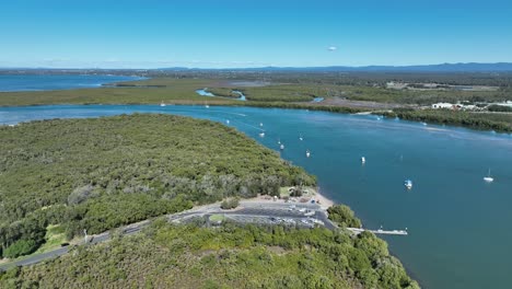 aerial drone shot orbiting beachmere boat ramps on caboolture river, boats in river opening to the ocean moreton bay