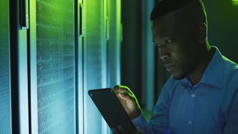 African-american-male-computer-technician-using-tablet-working-in-business-server-room