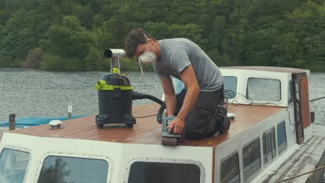 cinturón de carpintero joven lijado barco de madera cabina de proa quitando el barniz