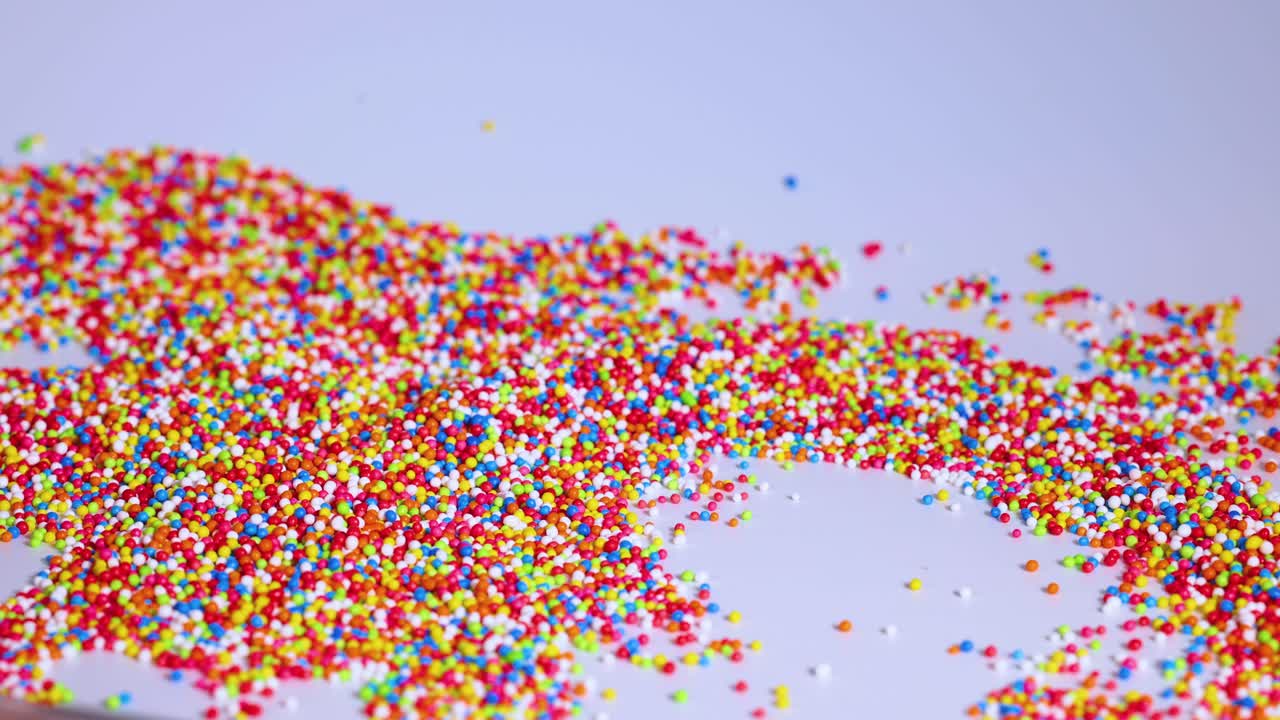 Spoon moves through vibrant sprinkles on surface
