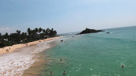 slow motion aerial shot over people swimming in warm water enjoying summer time, sri lanka