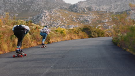 jóvenes amigos haciendo longboard juntos disfrutando de carreras competitivas navegando rápido cuesta abajo divirtiéndose montando en patineta usando casco protector vacaciones de verano deporte vista trasera