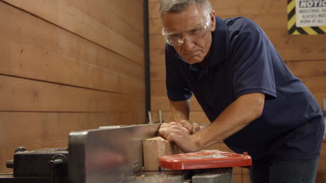 male carpenter using plane in woodworking woodshop