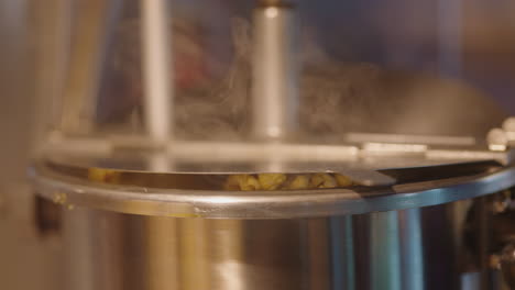 close up of popcorn cooking and steaming, overflowing out of stainless steel cooking pot, 4k