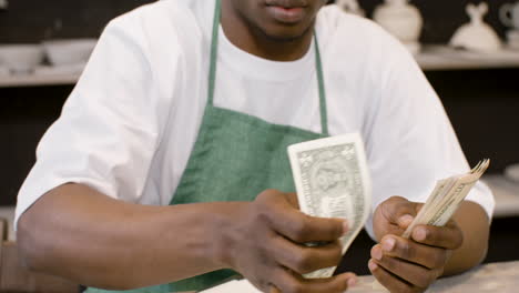 male small business owner counting money in the pottery shop