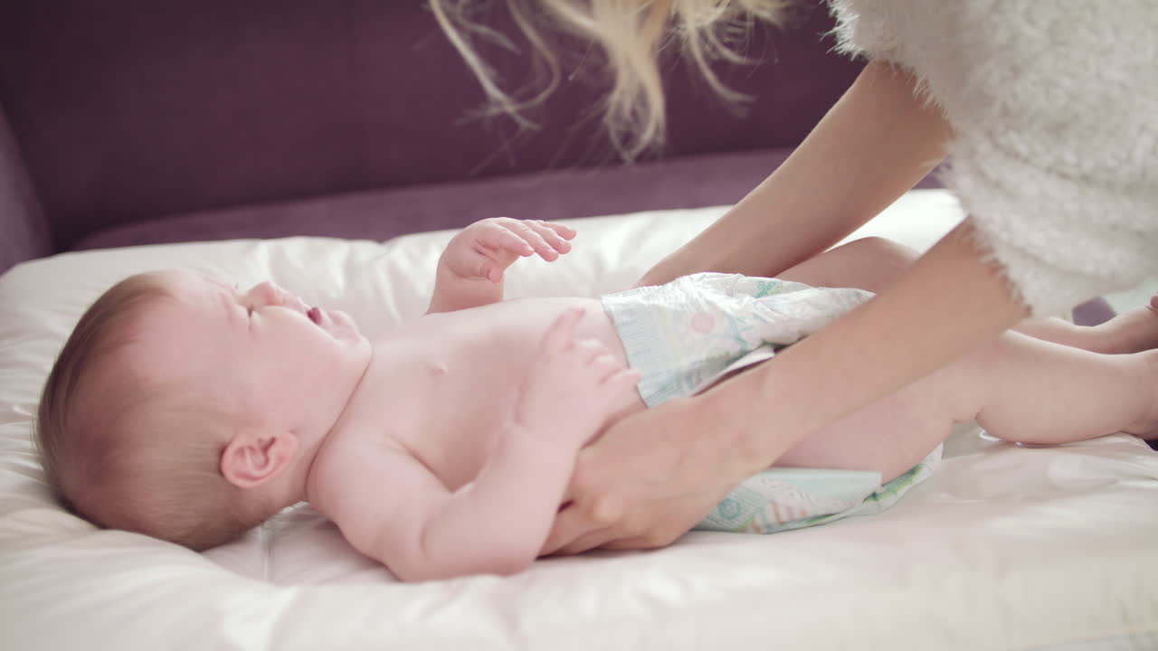 la madre cuida al bebé que llora. el bebé llora en pañales. el bebé llora en una servilleta blanca.
