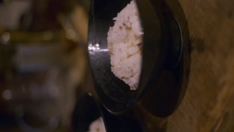 2 cuencos negros llenos de arroz sentados para enfriarse en una mesa de madera, filmados como una toma vertical de movimiento lento en primer plano.