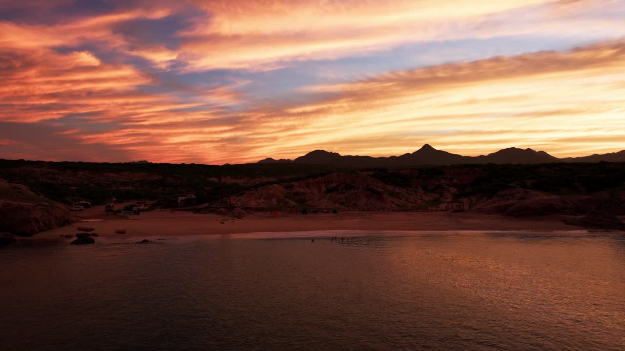 el atardecer rojo de fuego ilumina el cielo brillante, la silueta de las montañas cerca de cabo pulmo abajo