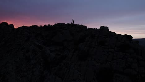 silhouette of person on mountain peak at sunset