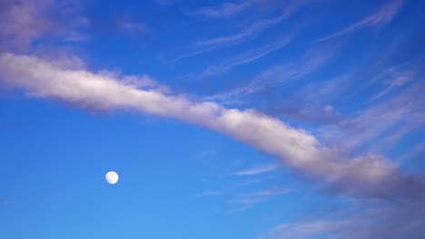 rising vertically full moon on clear blue sky during evening hiding temporarily behind long clouds. excellent video for video production as background or mixing with other films