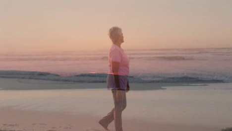 senior woman walking along shoreline, displaying animated heart icon and step count for health apps