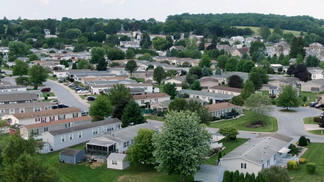 Aerial push-in descending shot on mobile trailer park, manufactured homes, compact small houses in neighborhood community, American town in rural suburbia, USA