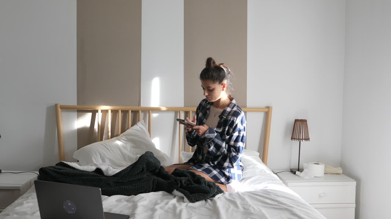 Teenager using a smartphone in a bedroom