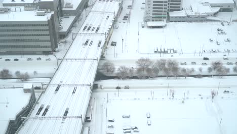 looking down on snowed in area with rail tracks and cars in snowed in urban area