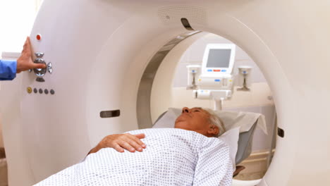 un paciente es cargado en una máquina de resonancia magnética mientras el médico y la enfermera miran
