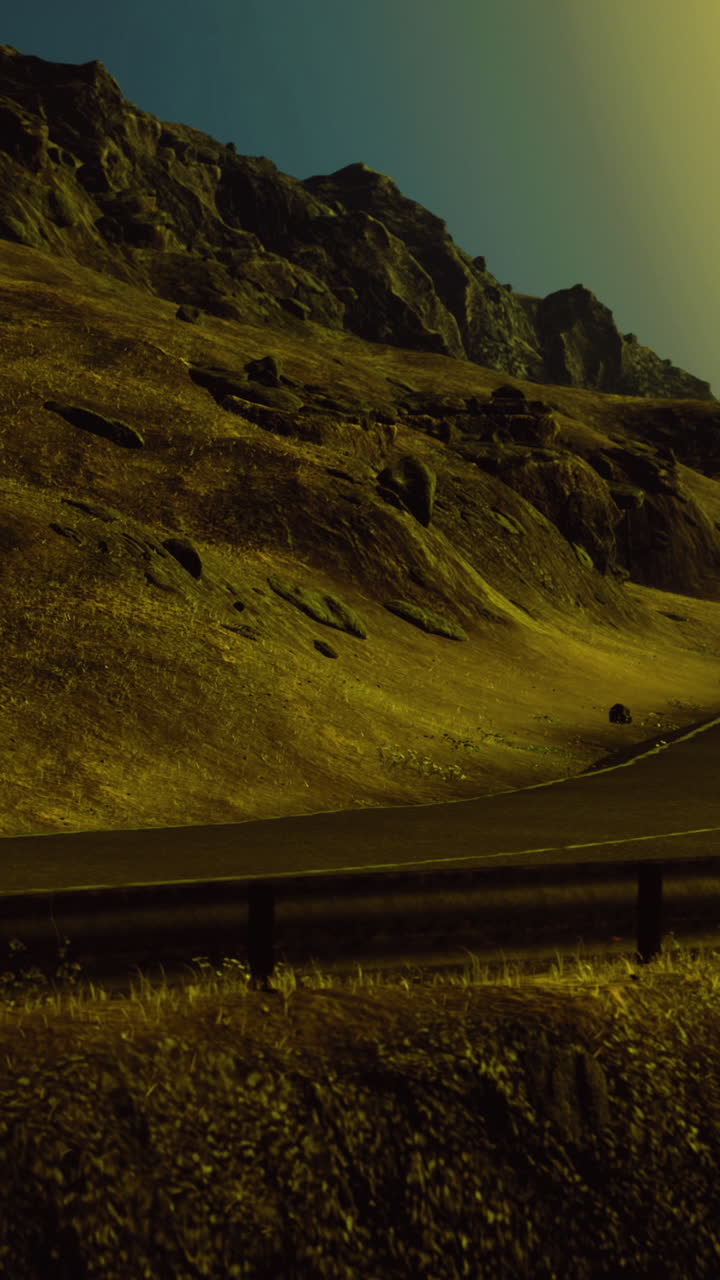 Curving mountain road under bright sun setting near rocky landscape