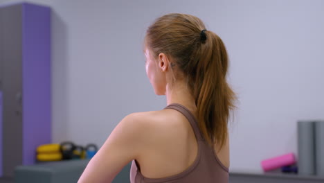 close up of young lady performing deep stretch and arm stretch in gym, surrounded by fitness equipment, focus on toned muscles and athletic form in well-lit exercise space