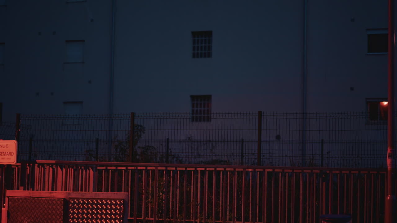 Nighttime shot of a train speeding past, with glowing interior lights visible through the windows