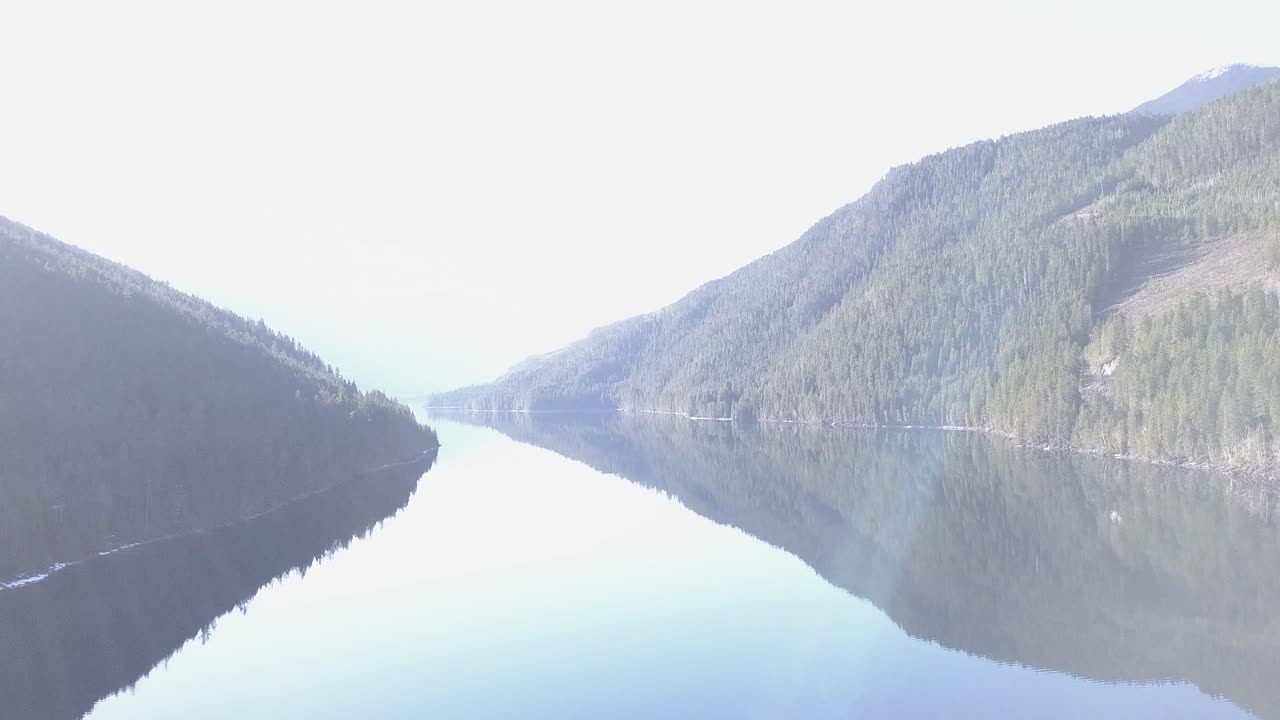 High key, ethereal panning mountain lake scene with lens flare