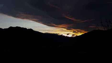 fiery sunset sky over mountain in silhouette - stunning view - time lapse