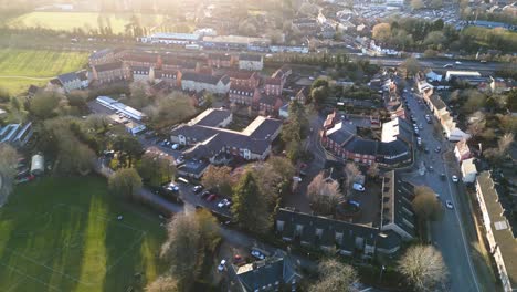 bury st edmunds with shadows indicating late afternoon light, showing buildings, roads, a soccer field, and parked cars, aerial view