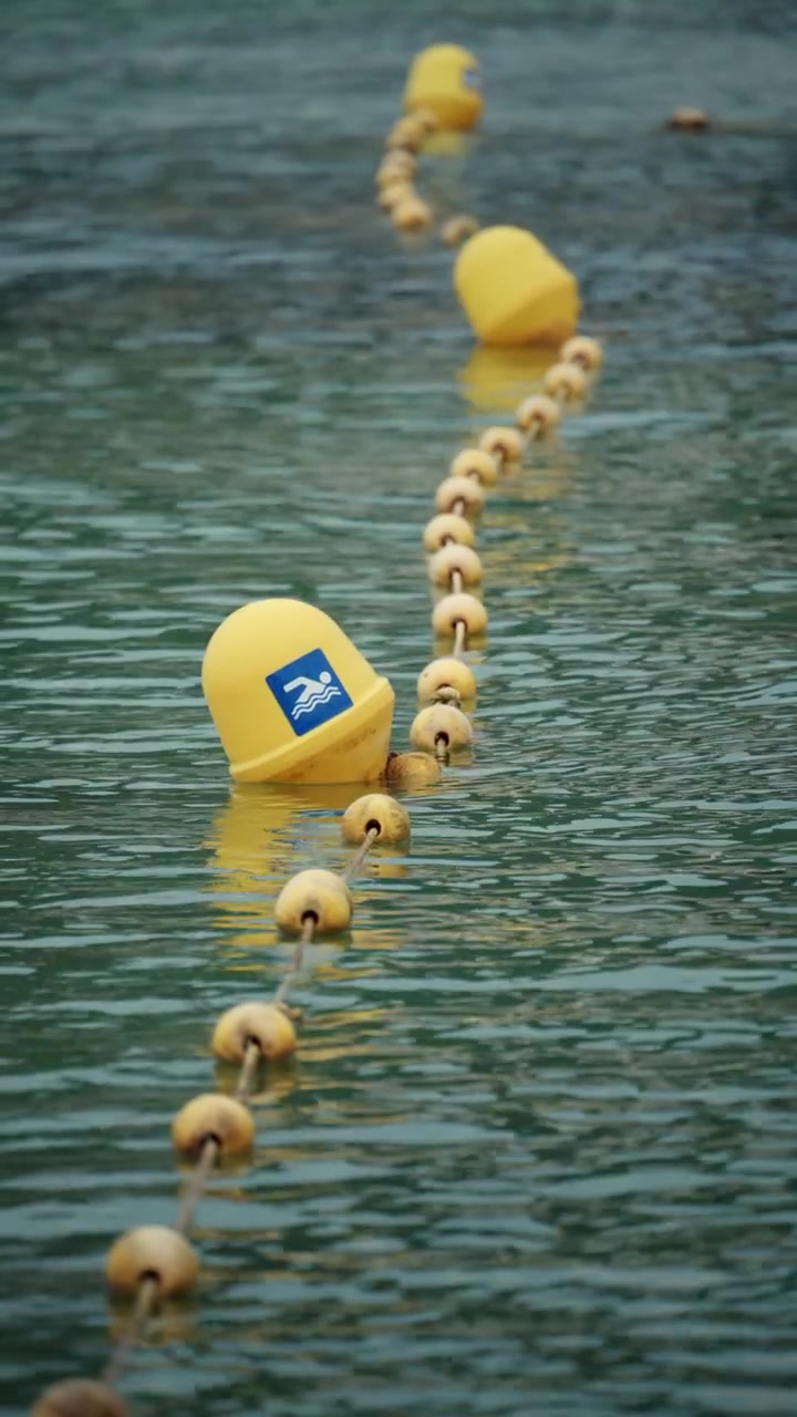 Yellow buoys and rope line floating on green water, clearly marking a safe swimming area limit