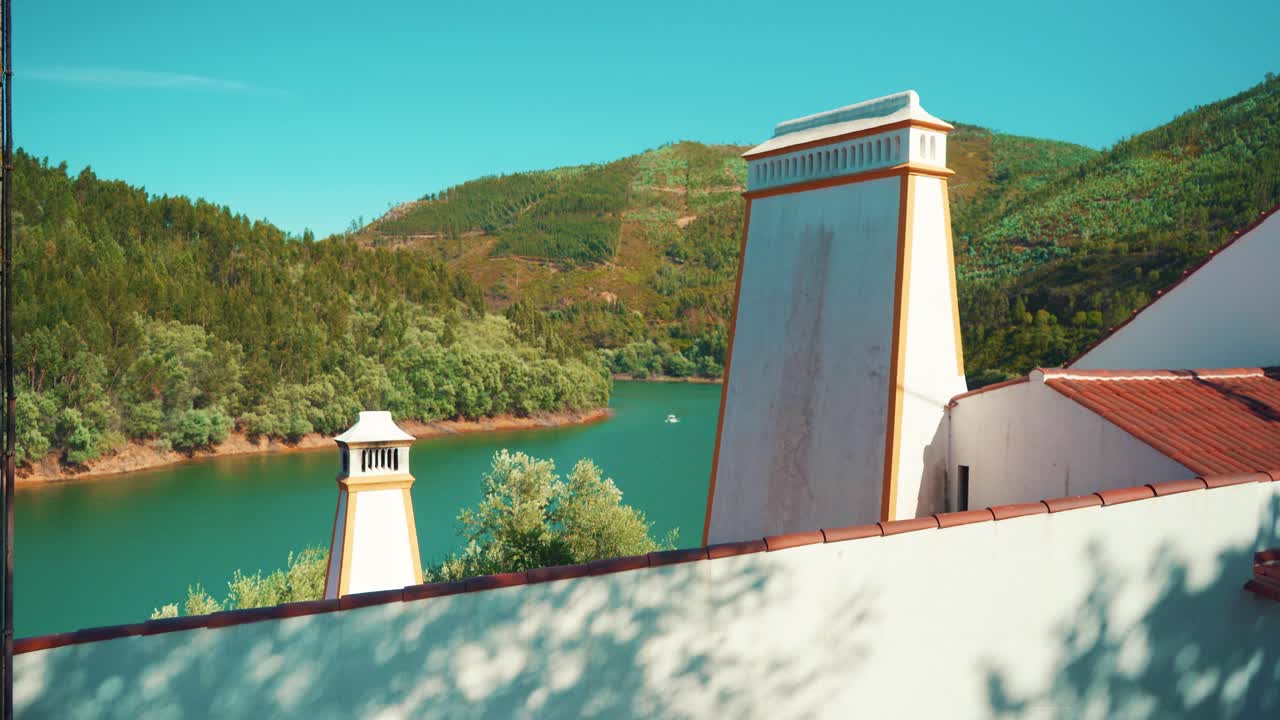 acercamiento del barco del río portugal al pueblo típico con chimenea en el techo, paredes blancas bajo el cielo azul al sol 4k