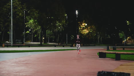 sportive sportswoman using bluetooth headphones running in the park at night