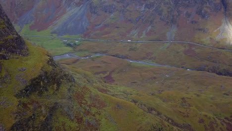 Aerial-travels-around-mountain-buttress-in-colorful-rugged-valley