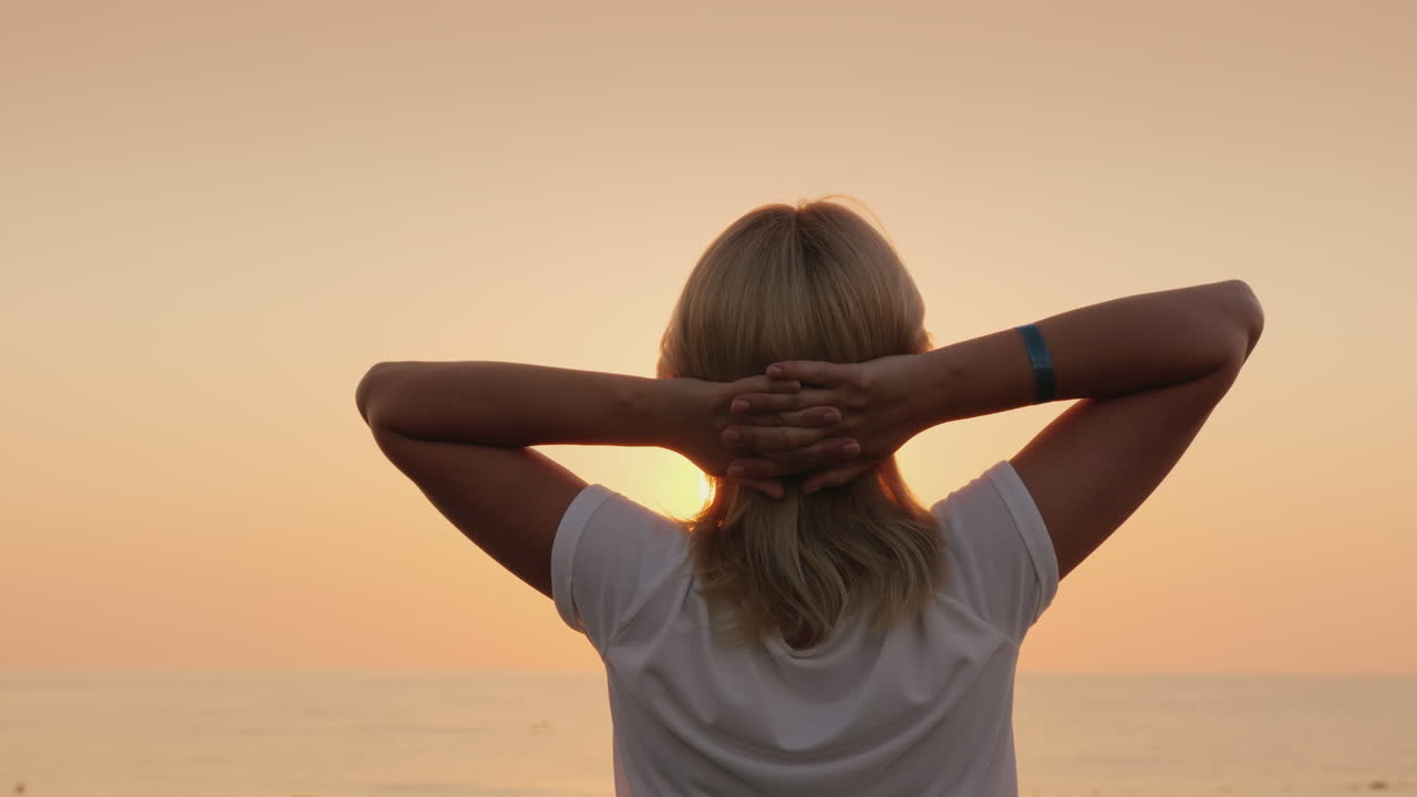 Una giovane turista dai capelli chiari incontra l'alba in riva al mare, si rilassa e si gode il silenzio. Vista del paesaggio.