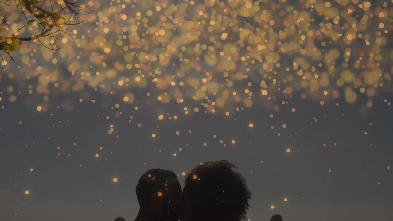 ロマンス映画、金色の光の火花が漂い、手すりにもたれかかるカップルを照らし、夜空の下でキスするシーン。