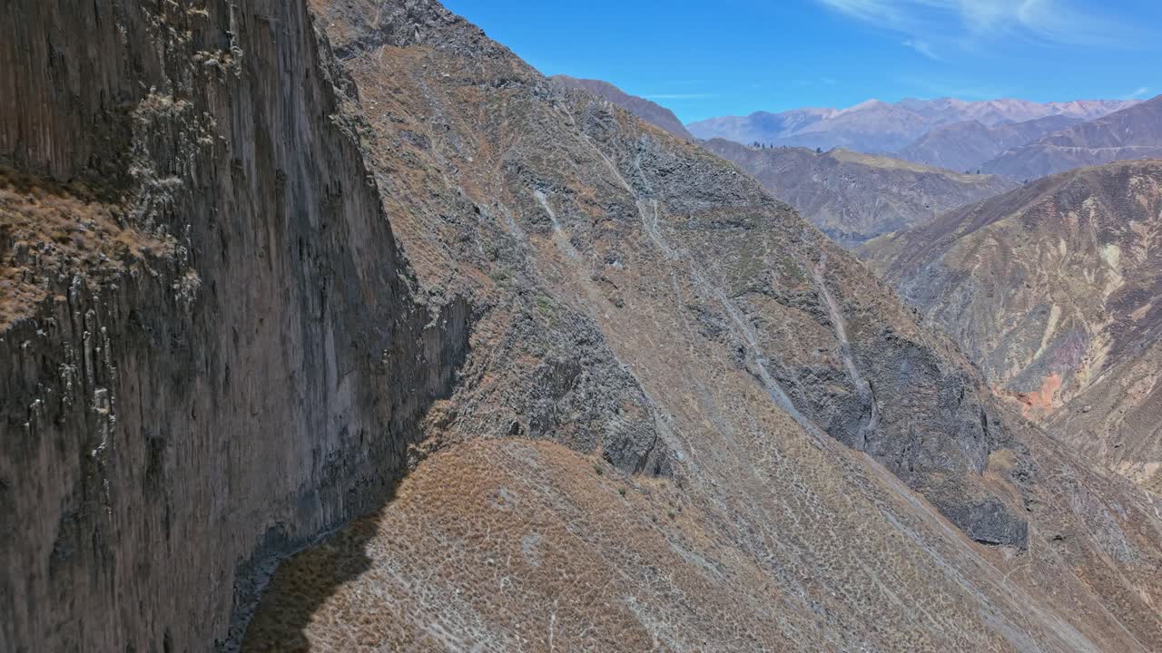 Un drone sorvola una delle enormi pareti rocciose a strapiombo all'interno del Canyon del Colca, Perù. Le scogliere frastagliate, le superfici texturizzate e la scala spettacolare del canyon creano un'esperienza paesaggistica potente e coinvolgente.