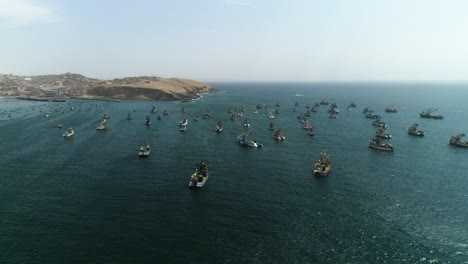 aerial view around fishing vessels moored on the coastline of sunny huacho, peru