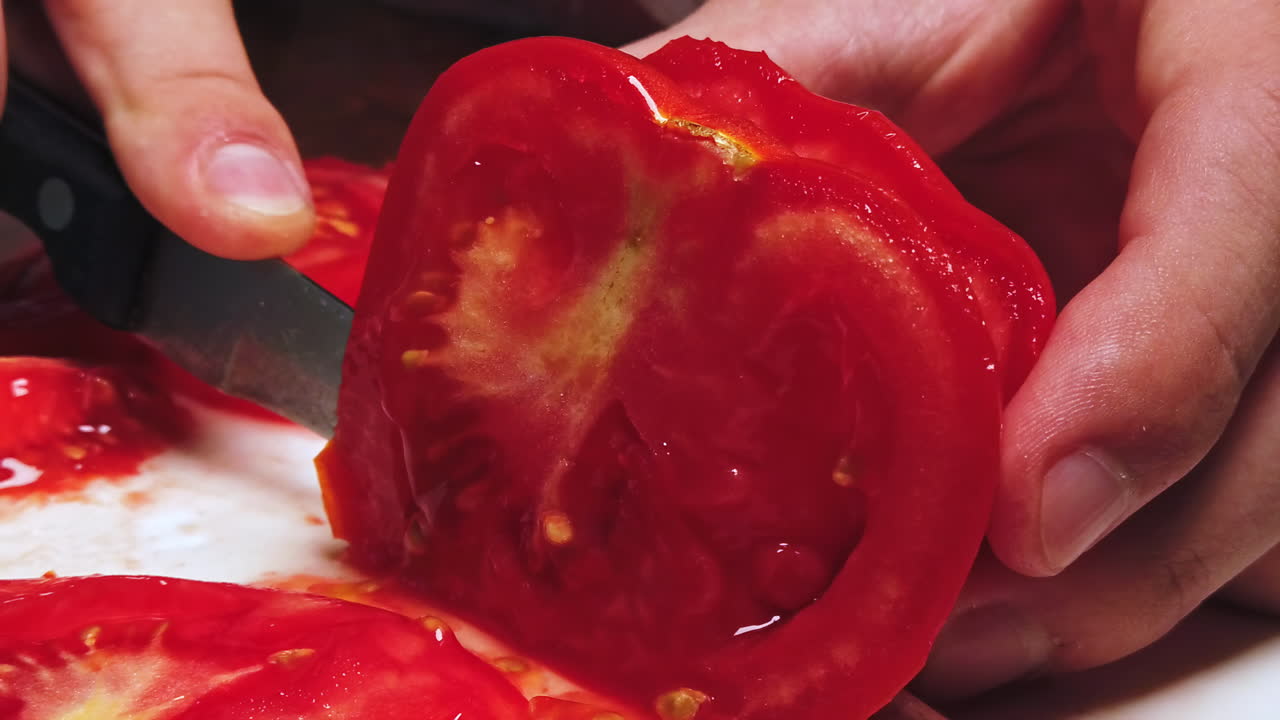 Close-up shot of a man cutting tomato on the desk in slowmotion